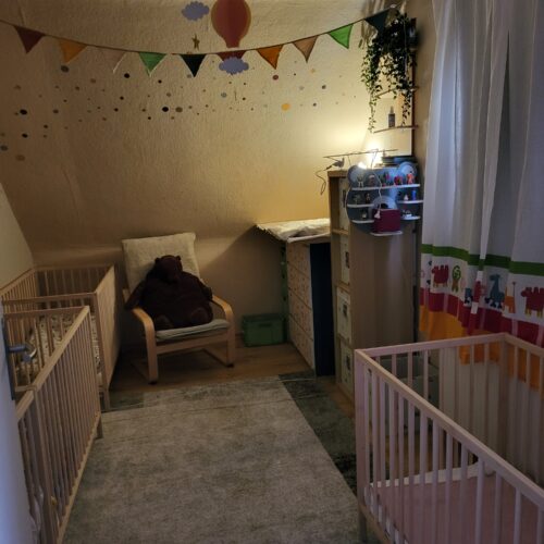 Gemutliches Kinderzimmer in Beige mit Girlanden Luftballons und zwei Holzbetten