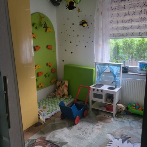 Farbiges Kinderzimmer ohne Personen mit Spielkueche und Bienenlampe
