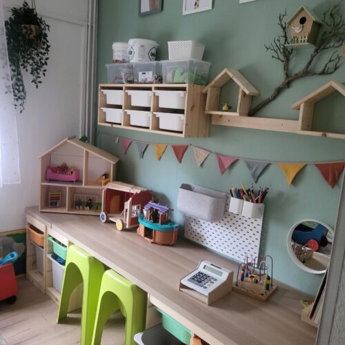 Aufgeraeumtes Kinderzimmer in Gruen mit Holzregal und Basteltisch